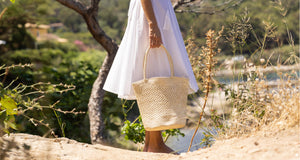 femme en robe blanche et panier d'osier micmac saint tropez sur une plage